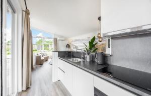 a kitchen with white cabinets and a black counter top at 2 Bedroom Lovely Home In Voorthuizen in Voorthuizen
