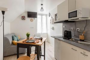 a kitchen and living room with a table and a couch at Charmant studio proche de toutes commodités in Saint-Quentin