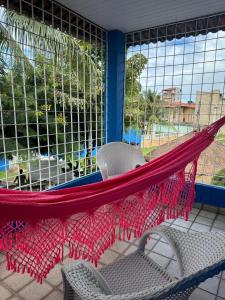 eine Hängematte auf einer Terrasse mit einem Stuhl und einem Fenster in der Unterkunft Carneiros House in Praia dos Carneiros