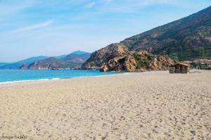 a beach with a small shack on it next to the water at Hôtel Le Golfe Ecolabel EU in Porto Ota