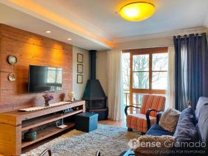 a living room with a couch and a tv at Apartamento a 300m da Rua Coberta de Gramado in Gramado