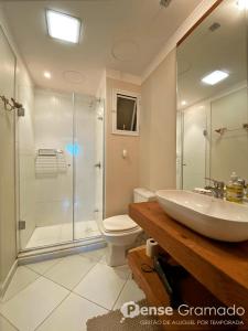 a bathroom with a shower and a sink and a toilet at Apartamento a 300m da Rua Coberta de Gramado in Gramado