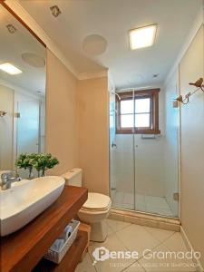 a bathroom with a toilet and a sink and a shower at Apartamento a 300m da Rua Coberta de Gramado in Gramado +13 photos