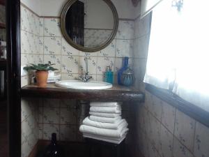 y baño con lavabo, espejo y toallas. en Casa Andrea, en Vejer de la Frontera