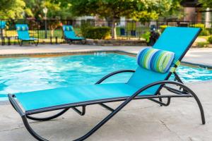 a blue lounge chair next to a swimming pool at Upscale City Apartment with Pool , Fitness Center in Carrollton