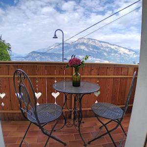 a table with two chairs and a vase of flowers on a balcony at Cà sul dos in Trento