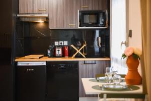 a kitchen with a black dishwasher and a microwave at Le Terra Rosa ~ Parking ~ Proche Airbus in Colomiers