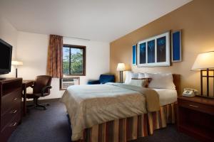 a hotel room with a bed and a desk and a television at Days Inn by Wyndham Austin in Austin