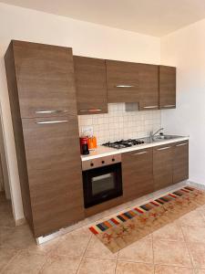 a kitchen with wooden cabinets and a stove at Appartamento il Delfino - Beach House in Isola Rossa