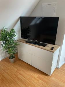 a large flat screen tv sitting on a white cabinet at Q2 Apartment Hannover Döhren mit Ausblick in Hannover