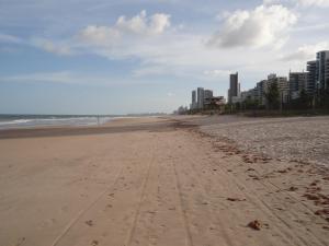 a beach with footprints in the sand and buildings at Loft Portal Beach 01 in Recife