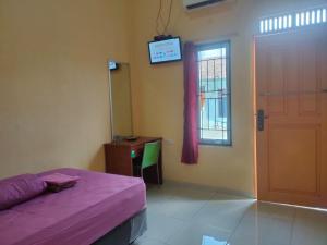 a room with a bed and a desk and a window at Serasikostel in Sukarami