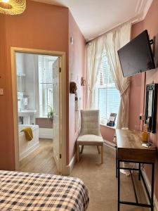 a bedroom with a bed and a desk and a television at The Boho - 4 min walk to beach & town in Bournemouth