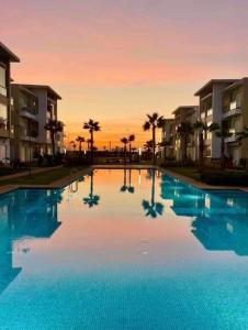 a large swimming pool with a sunset in the background at F3 Casabay beach sidi rahal vue sur piscine in Sidi Rahal +5 photos