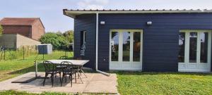a table and chairs in front of a blue house at Maison de ressourcement au calme in Beuvry