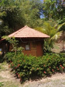 ein kleines Haus mit einem gefliesten Dach in einem Garten in der Unterkunft Ecopousada Casa do Carimbó Fortalezinha in Algodoal