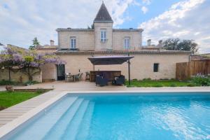 a villa with a swimming pool in front of a house at Le jardin de Gassiot in Saint-Quentin-de-Baron