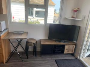 a living room with a tv and a table and a stool at Ohana in Leysdown-on-Sea