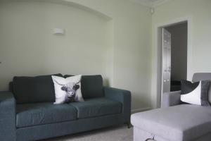 un salon avec un canapé vert avec un coussin pour chien dans l'établissement 2 BDR House At Caledonia Luxe Stays Short Lets & Serviced Accommodation Lanark, à Lanark