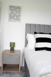 a bedroom with a bed and a nightstand with a lamp at Rhyber Avenue in Lanark