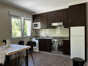 a kitchen with brown cabinets and a table and a kitchen with a refrigerator at Apartamentos Toffe in Outes