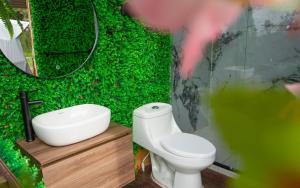 bagno con parete verde, servizi igienici e lavandino di Glamping Yáku a Tenjo