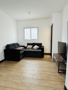 a living room with a black couch and a television at Casa condominio bosques de Santa Elena in El Durazno