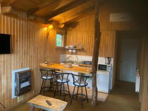 a kitchen with a counter with stools and a stove at Cabañas el Bosque Patagónico in Frutillar