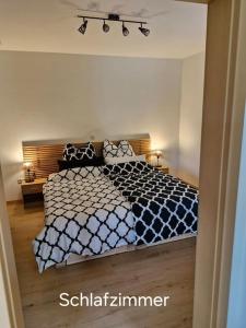 a bedroom with a bed with a black and white comforter at Ferienwohnung Edgar und 300 qm Garten Trier Mosel Eifel in Mertesdorf