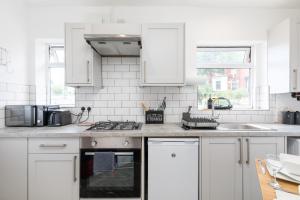 海丁利Stylish Studio Apt in Leeds的厨房配有白色橱柜和炉灶烤箱 更多7张照片