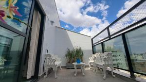 a balcony with white chairs and a table and windows at Athos Bulcão - Cobertura Duplex - Un 1519 in Brasilia