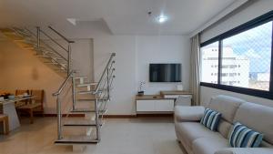 a living room with a couch and a spiral staircase at Athos Bulcão - Cobertura Duplex - Un 1519 in Brasilia