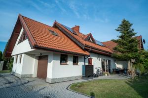 a white house with an orange roof at Willa Świniarsko z basenem in Podrzecze