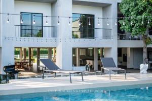 a pool with two chairs next to a building at Pirom Garden Private Villa in North Pattaya +56 photos