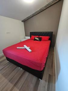 un lit rouge avec une couverture rouge et deux objets dessus dans l'établissement Maison avec jardin proche gare, à Belleville-en-Beaujolais