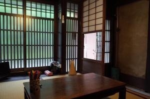 a room with a wooden table and windows at 京町家 近よし in Kyoto