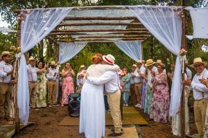 une mariée et un marié s'embrassant sous une arche en bois dans l'établissement Happy Hour no Condo- Minions, à Riacho Grande 90 autres photos