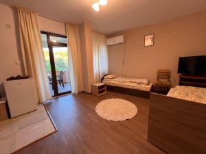 a living room with a bed and a television at Вихрен-стаи и апартаменти за гости in Sandanski