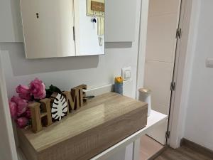a kitchen counter with a white cabinet and pink flowers at Acogedor Apartamento in Almerimar