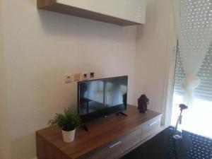 TV de pantalla plana en la parte superior de un centro de entretenimiento de madera en Zoa Apartment, en Torrevieja