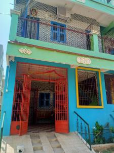 a blue building with red doors and a balcony at Linga Wooden Room Second floor in Kanchipuram +6 photos
