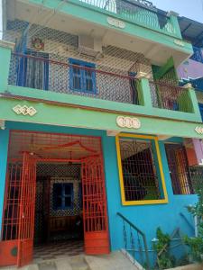 a colorful house with red doors and a balcony at Linga Wooden Room Second floor in Kanchipuram