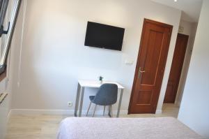 a bedroom with a desk and a television on the wall at Hostal Paz in Gondomar +46 photos