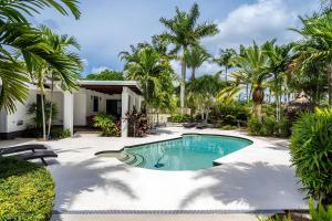 a swimming pool in a yard with palm trees at October Pink Miami SW Stunning Garden & Pool in Homestead