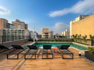 a rooftop patio with chairs and a pool on a building at Condomínio com piscina ao lado do Parque Buenos Aires in Sao Paulo
