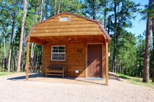 a small wooden shed with a door and a bench at Pine Haven Lodging in Rockerville