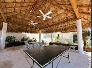 a ping pong table under a thatched roof at Villa MAJUM Acapulco in Acapulco