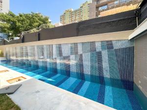 einem Pool mit blauen Fliesen an der Seite eines Gebäudes in der Unterkunft Handy Paraíso condomínio com piscina ao lado do Ibirapuera in São Paulo