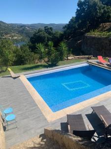a swimming pool with two chairs and a table at Paraiso Relax no Douro in São Cristóvão da Nogueira