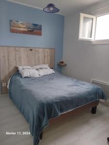 a bedroom with a bed with a blue comforter at Les Pieds Dans L'eau Accés direct à la plage in La Cotinière